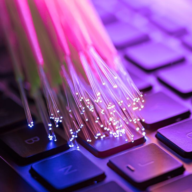 Fascio di cavi in fibra ottica con estremità illuminate sopra la tastiera di un computer